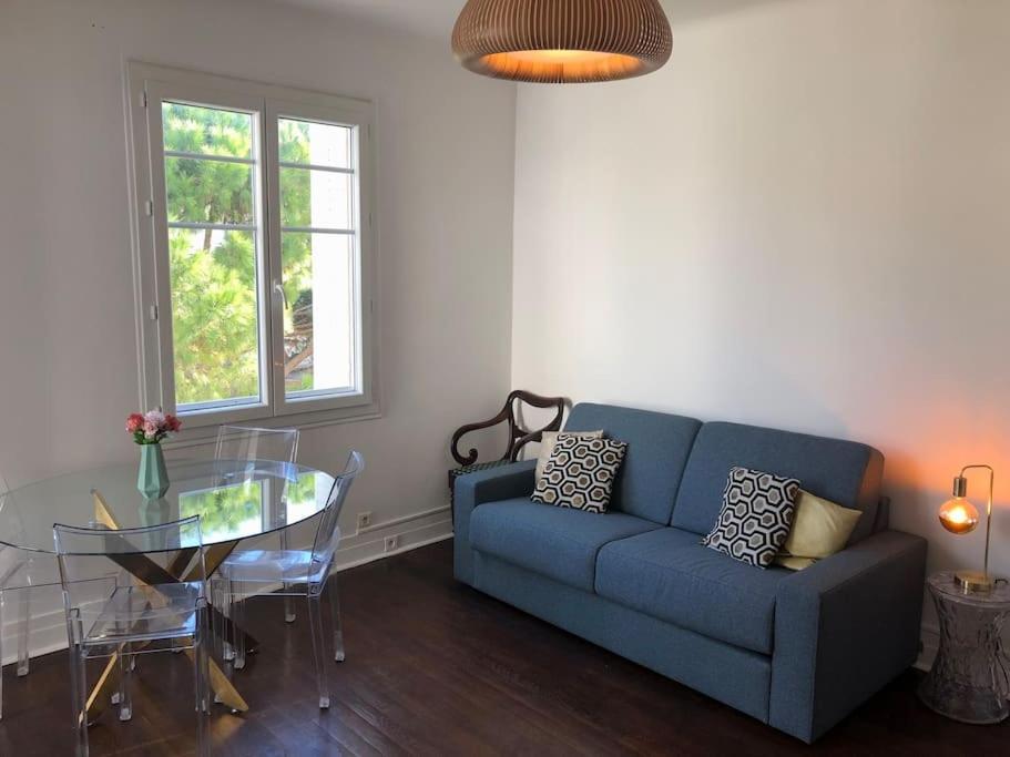 ein Wohnzimmer mit einem blauen Sofa und einem Glastisch in der Unterkunft Charming &amp; quiet appart 10 from beaches in Cannes