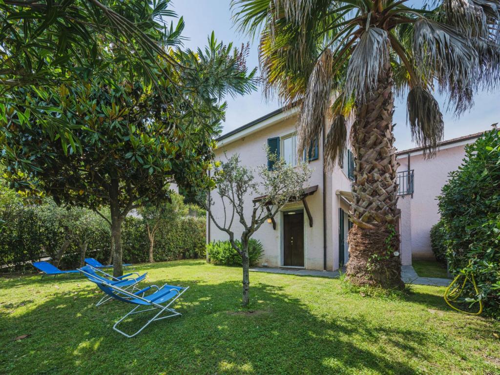 a house with a palm tree and two lounge chairs at Holiday Home Lucerna Due-3 by Interhome in Ameglia
