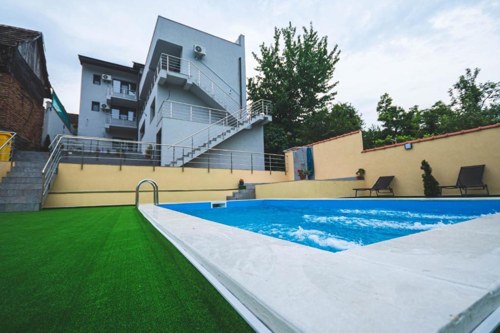 a swimming pool with green grass next to a building at La Roby si Niko in Dubova