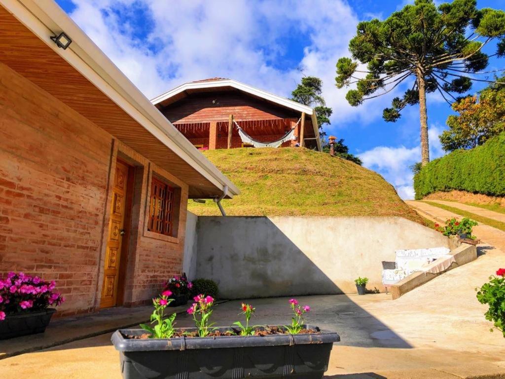 a house with a grassy hill behind it at Casa Aconchegante na Montanha in Campos do Jordão