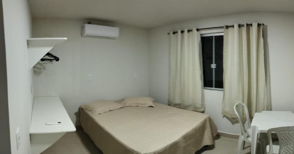 ein kleines Schlafzimmer mit einem Bett und einem Fenster in der Unterkunft Residencial Casa Grande - Apto 03 in Santa Cruz Cabrália