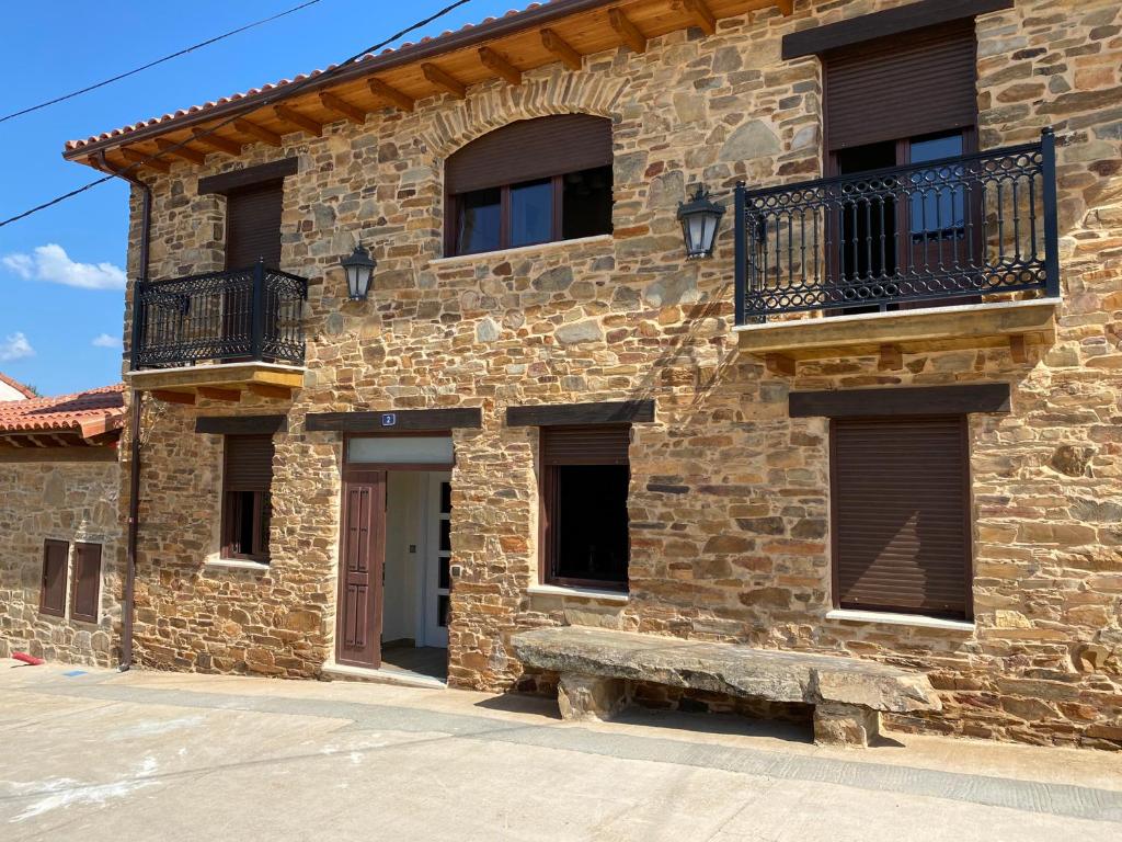 un edificio de piedra con un banco delante en Casa Amada con piscina, en Murias de Pedredo