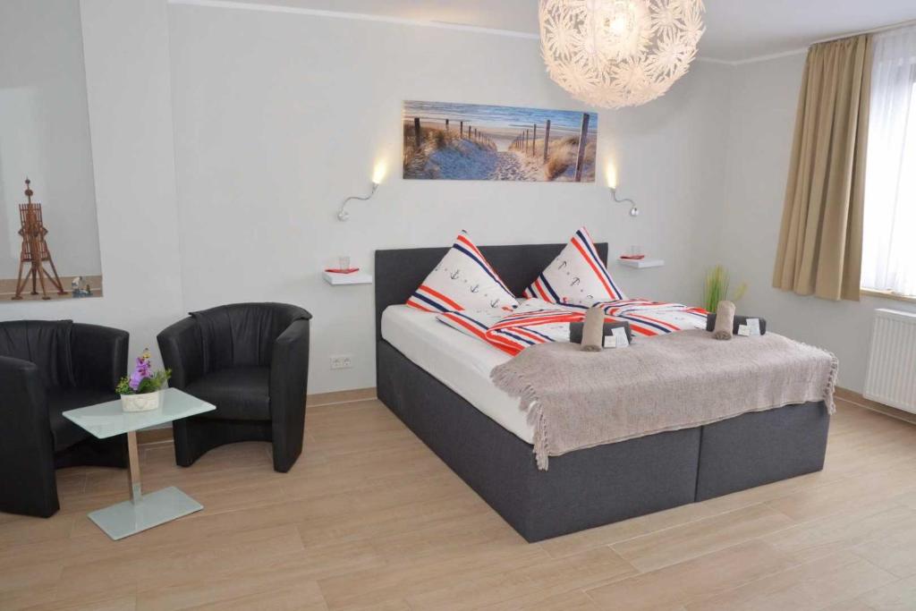 1 Schlafzimmer mit einem Bett, 2 Stühlen und einem Kronleuchter in der Unterkunft Hotel Neptuns Ankerplatz in Cuxhaven