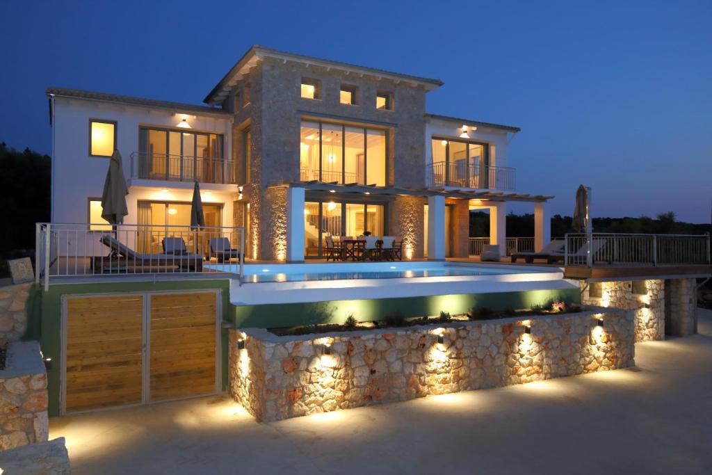 a house with a swimming pool with lights in front of it at Tsakmakis Villas Luxury- Panoramic Sea View - Lefkada in Tsoukaladhes