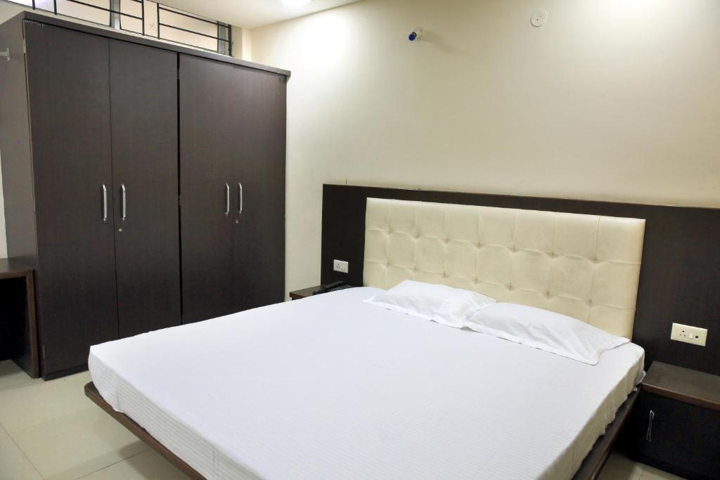 印多爾的住宿－Hotel Shri Raam Krishna Baag Indore，卧室配有一张大型白色床和黑色橱柜。