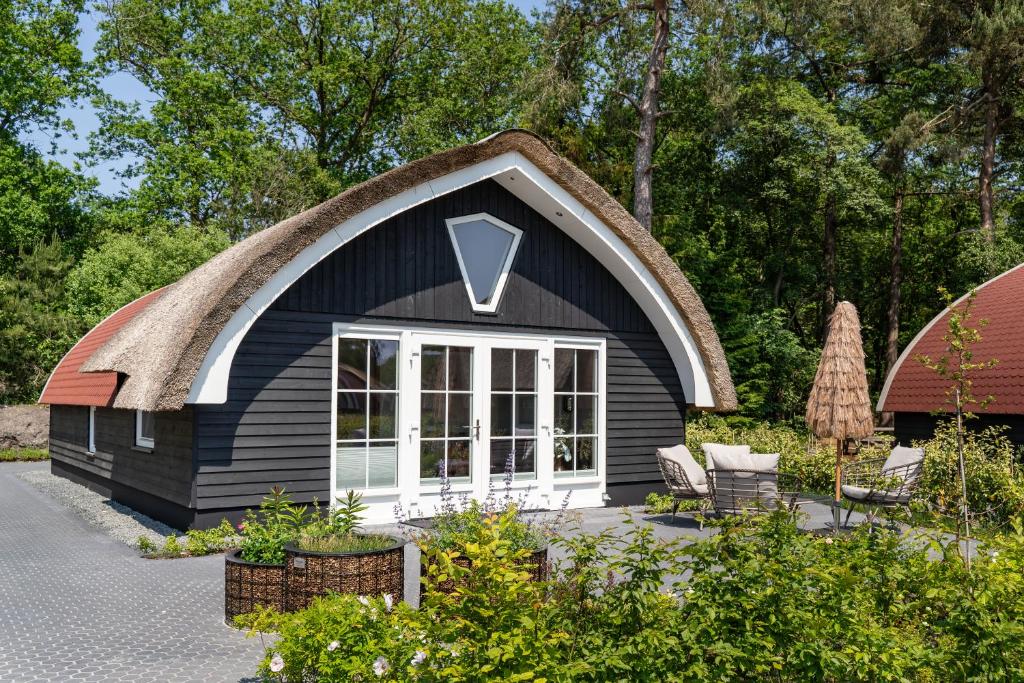 Ce petit cottage noir dispose d'un toit de chaume. dans l'établissement 't Landgoed Baars, à Baars