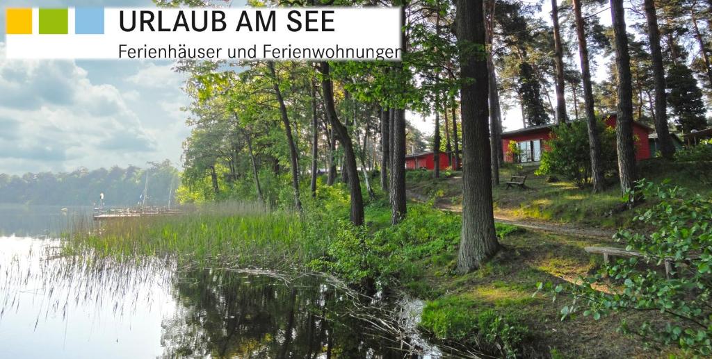 ヴェンディッシュ・リーツにあるFerienpark am Glubigseeの赤い小屋を背景に湖の景色を望む