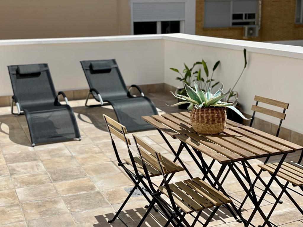 a wooden table and chairs with a potted plant on it at Apartamentos La Hormiga Deluxe in Adra