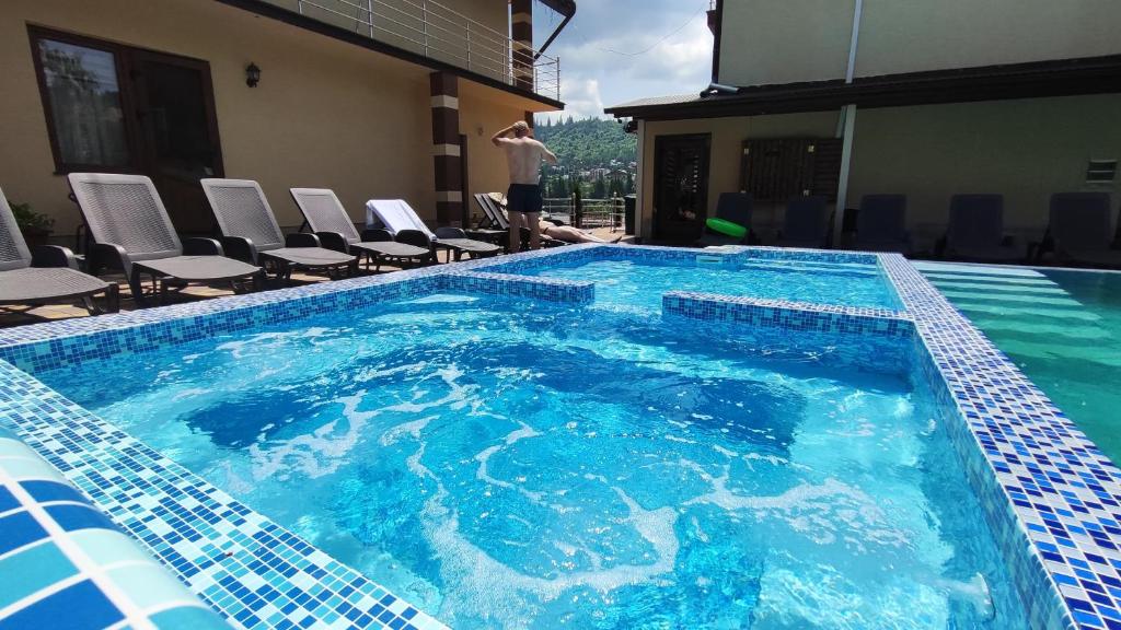 a large swimming pool with a man standing next to it at Villa Anet in Bukovel