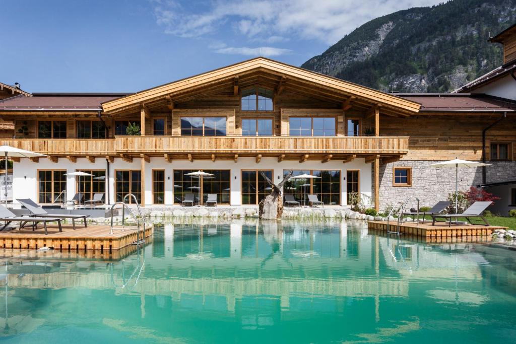 una casa de madera con una piscina frente a ella en NOVA Moments Boutique Hotel en Pertisau