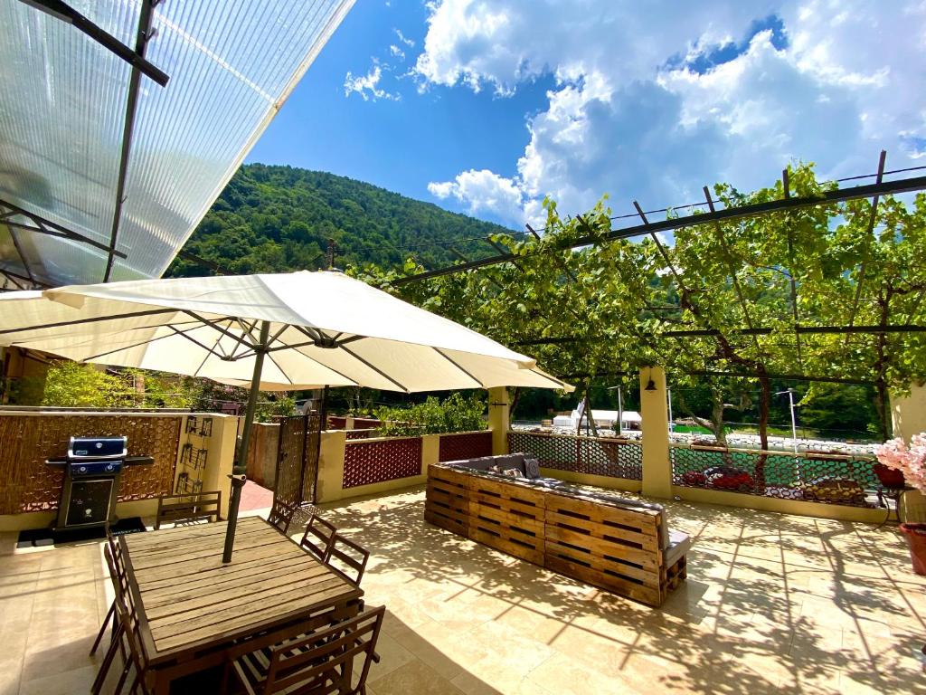 un patio con mesa y sombrilla en Appartement terrasse vue lac, en Breil-sur-Roya