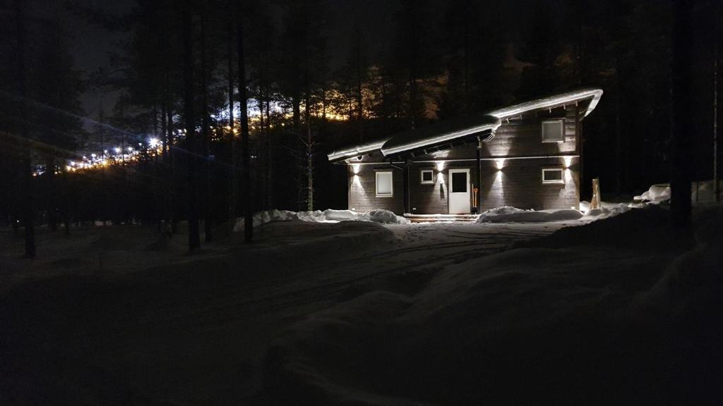 a small wooden cabin in the snow at night at Holiday home Villa Esteri in Pyhätunturi