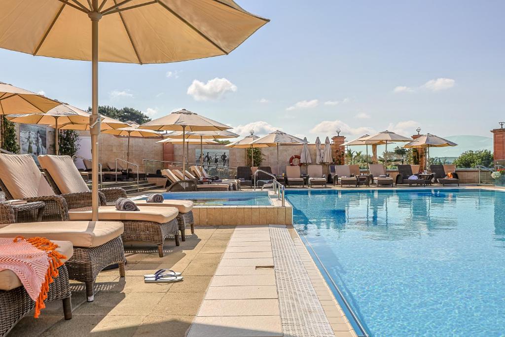 a swimming pool with chairs and umbrellas at Thurlestone Hotel in Thurlestone