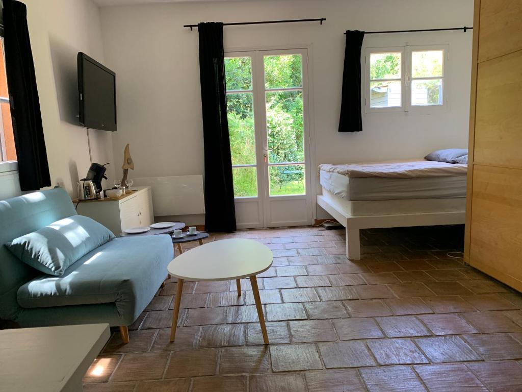 a living room with a couch and a bed and a table at le calme chambre 2 in Saint-Tropez