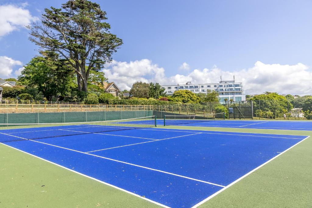 a tennis court with a blue court at Thurlestone Hotel in Thurlestone