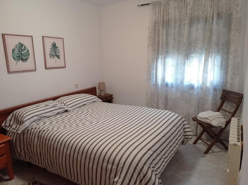 1 dormitorio con 1 cama, 1 silla y 1 ventana en El Olivar, en La Adrada
