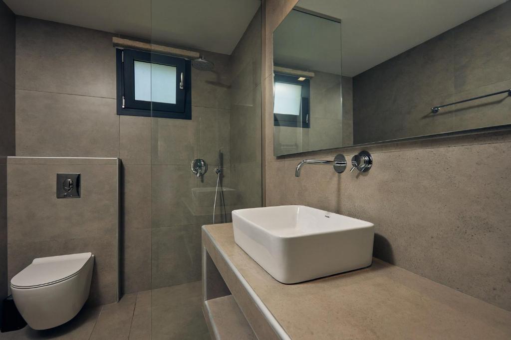 a bathroom with a sink and a toilet and a mirror at Mouzaki's Stone Villas in Volímai