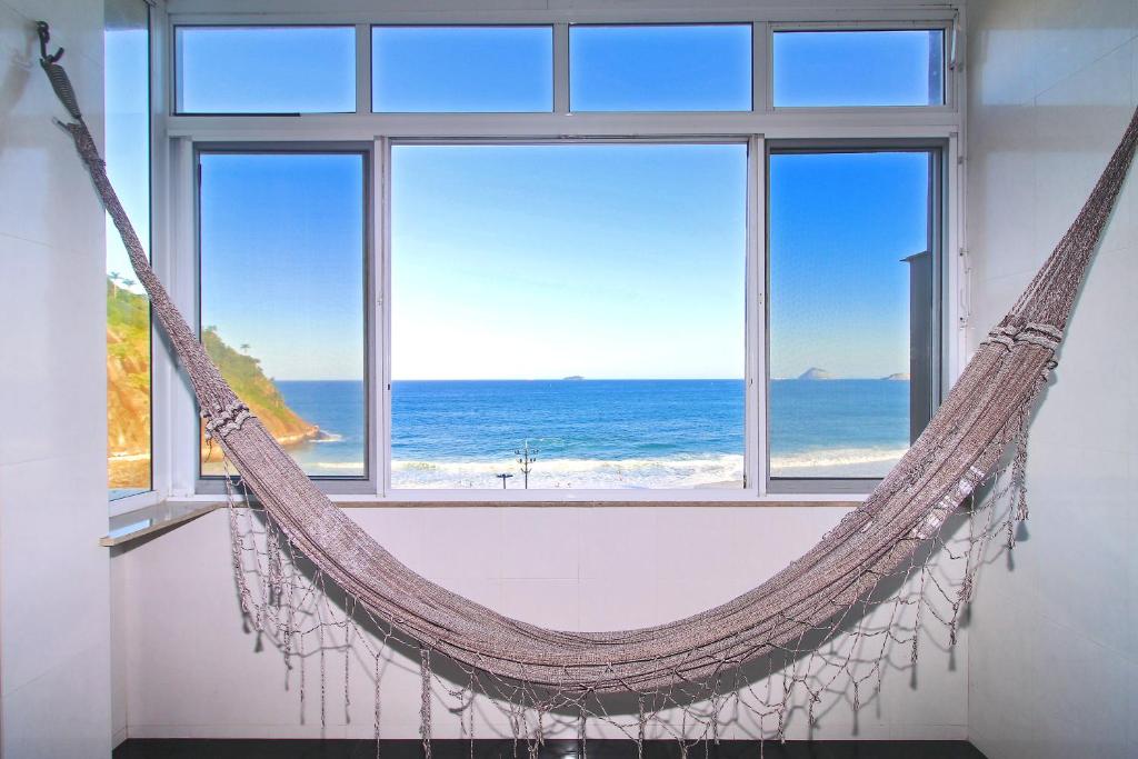 a hammock in a room with a view of the ocean at Rio Spot Homes vista praia D047 in Rio de Janeiro