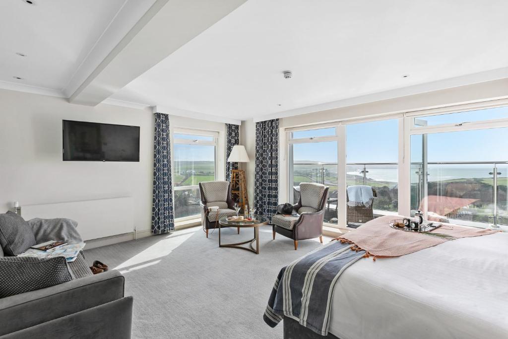 a bedroom with a large bed and chairs and windows at Thurlestone Hotel in Thurlestone