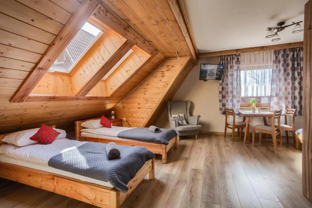 a attic bedroom with two beds and a table at U Studniara in Murzasichle