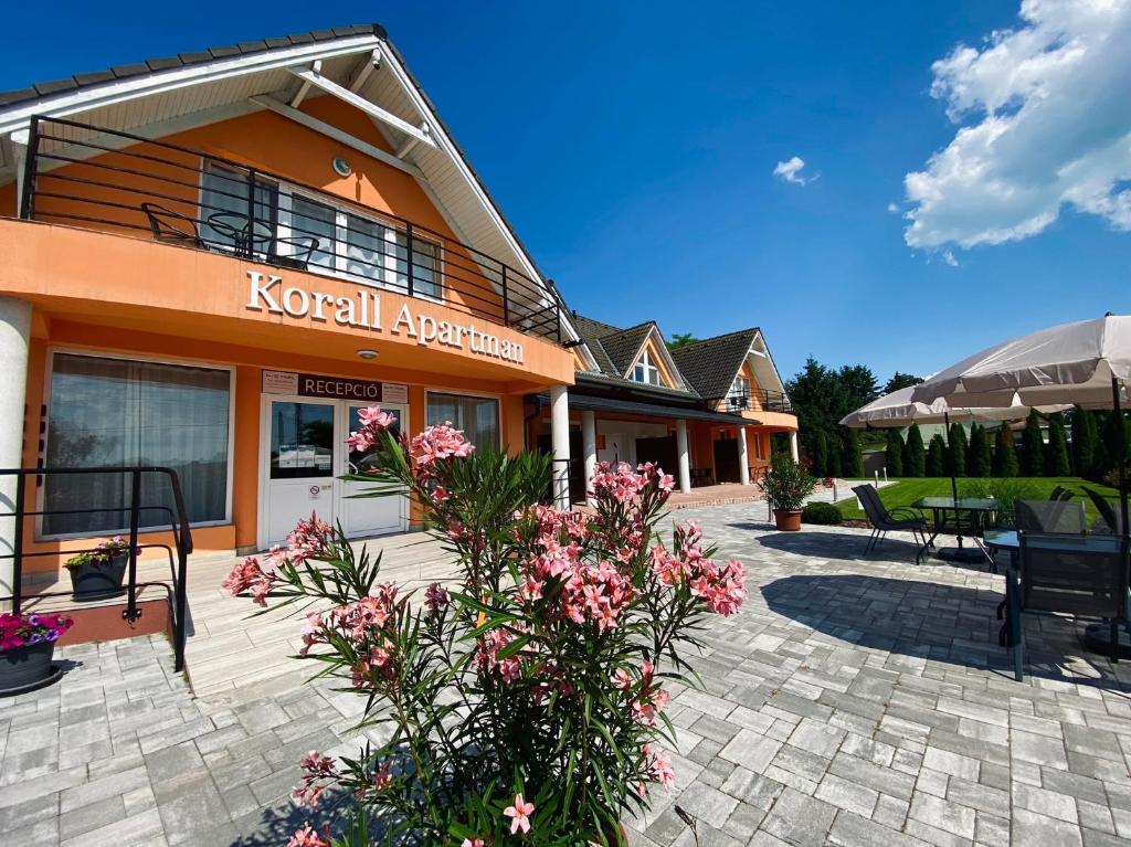 a building with a patio with flowers in front of it at Korall Apartman in Balatonfůzfő
