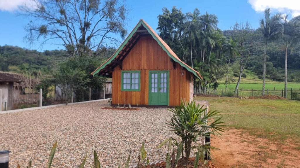 uma pequena casa com uma porta verde num quintal em Liebe Platz Chalé em Pomerode