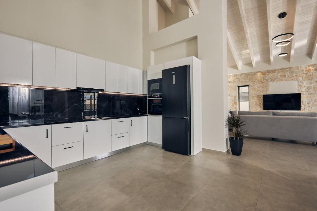 a kitchen with white cabinets and a black refrigerator at Mouzaki's Stone Villas in Volímai