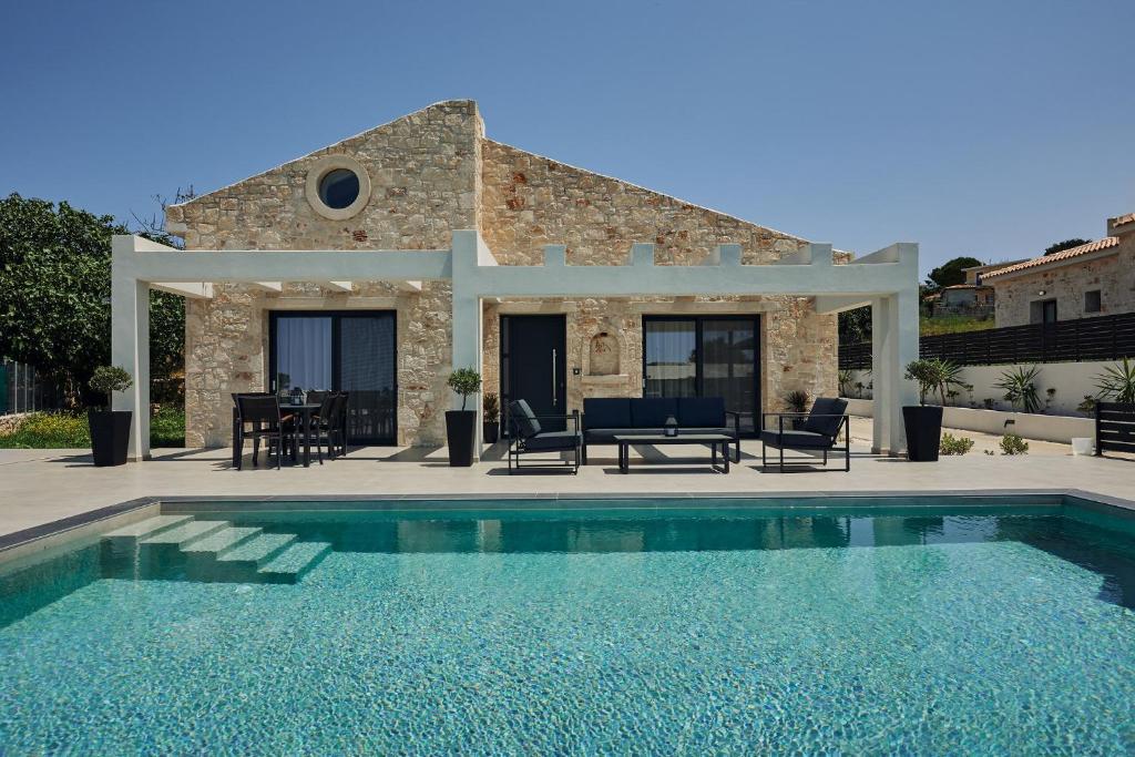 a villa with a swimming pool in front of a house at Mouzaki's Stone Villas in Volímai
