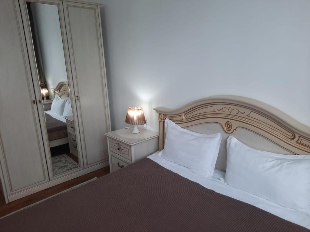a bedroom with a bed with white pillows and a mirror at Апарт отель Welcome in Taldykorgan