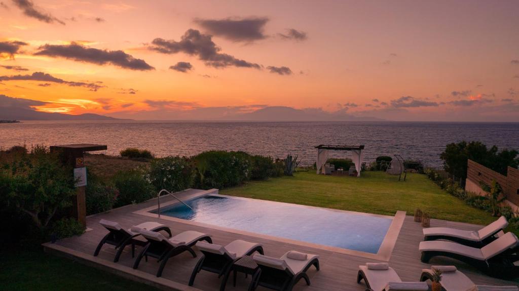uma piscina com cadeiras e um pôr-do-sol sobre a água em Sea Breeze Villa em Tsilivi