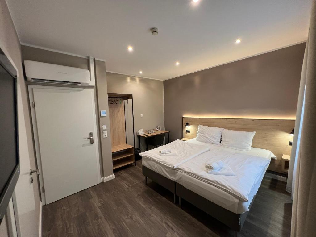 una camera da letto con un grande letto con lenzuola bianche di JJ Hotel Hannover-City-Pension ad Hannover