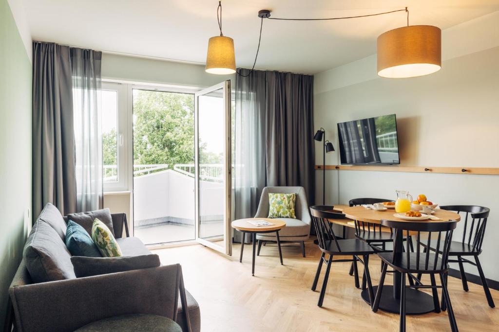 a living room and dining room with a table and chairs at harry's home hotel & apartments in Berlin