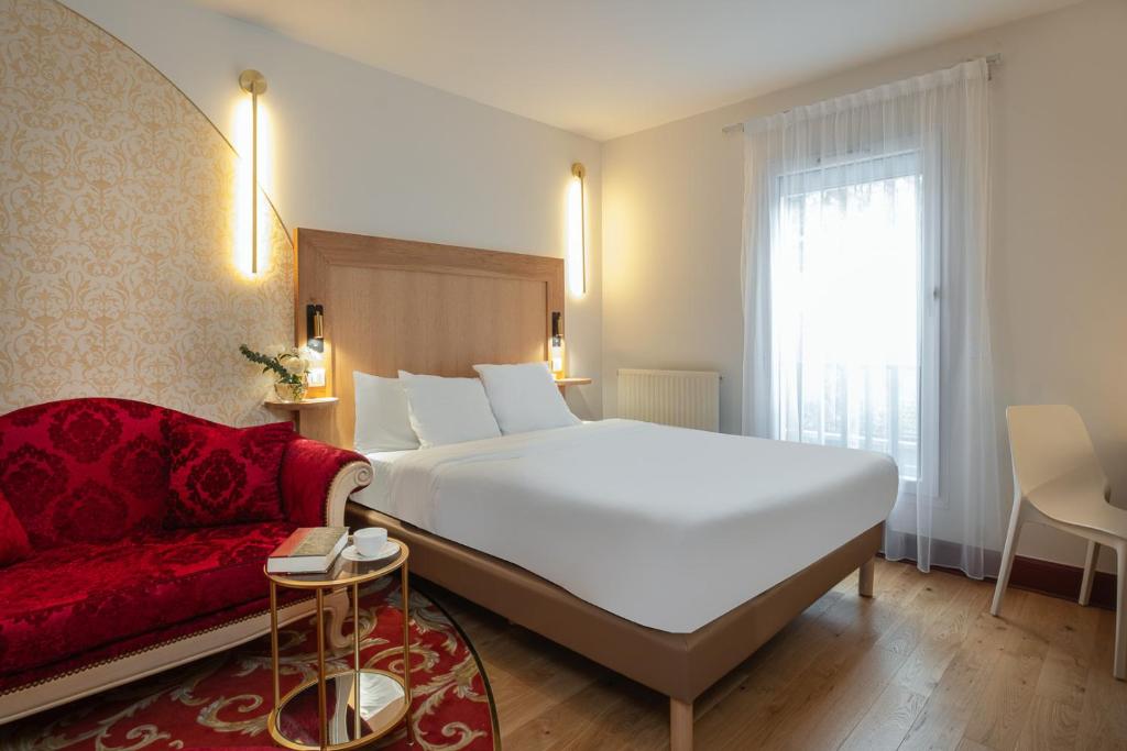 - une chambre avec un grand lit blanc et un canapé rouge dans l'établissement L'Orangerie du Château des Reynats, à Chancelade