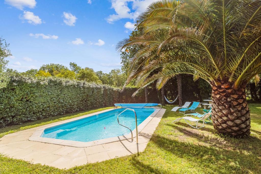 una palmera está al lado de una piscina en Villa Saint-Georges - Welkeys, en Saint-Georges-dʼOléron