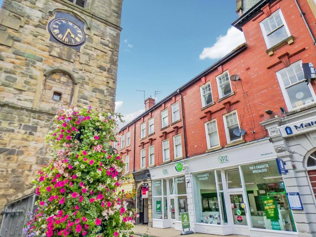 a building with a clock and flowers in front of it at Clock Tower Flats Morpeth in Morpeth