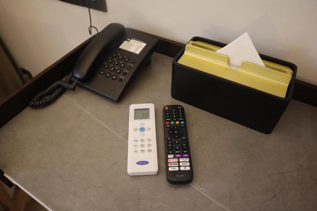 a phone and remote controls sitting on a desk at The Brunei Hotel in Bandar Seri Begawan