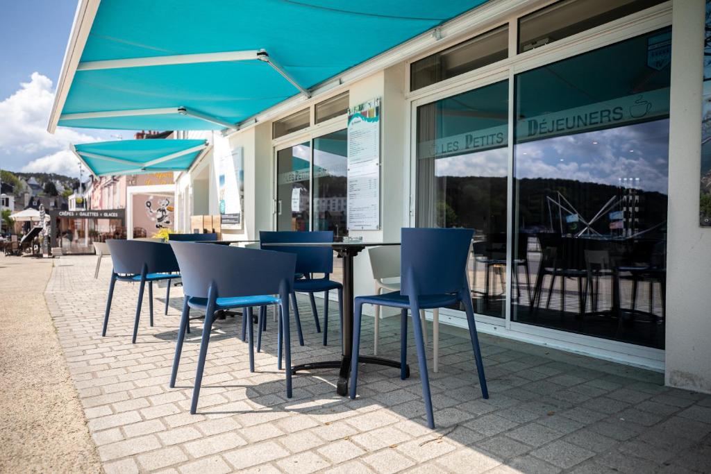 a group of chairs and tables with blue umbrellas at Hôtel de la Baie in Crozon