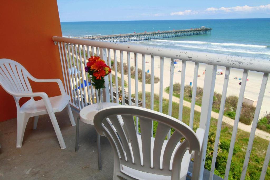 uma varanda com duas cadeiras e um vaso de flores e a praia em Bar Harbor em Myrtle Beach