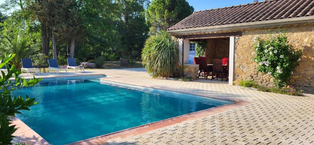 a swimming pool with chairs and a house at Domaine De L'aube Des Temps in Raissac-dʼAude