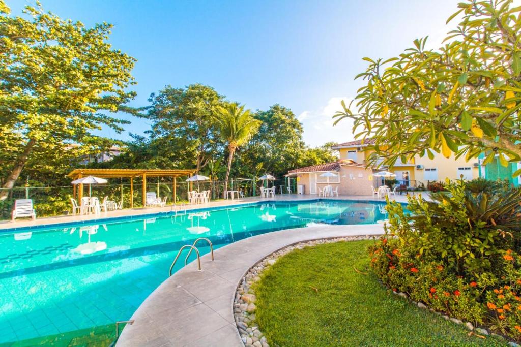 a swimming pool with chairs and trees in a yard at Apart Hotel Boulevard da Praia - Portal Hotéis in Porto Seguro