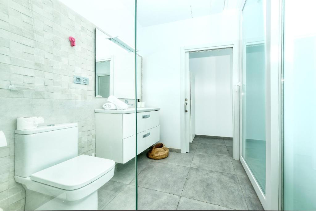 a bathroom with a toilet and a glass shower at Karma Famara 2 25m del mar in Famara
