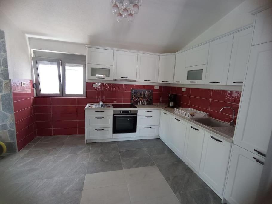 a kitchen with white cabinets and red walls at Villa Mona Liza in Dobra Voda