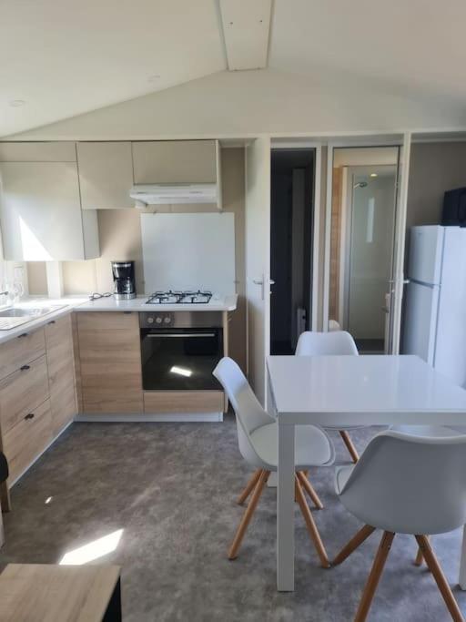 - une cuisine avec une table blanche et des chaises blanches dans l'établissement Mobil-home Magnolia 300m de la plage Ambleteuse, à Ambleteuse
