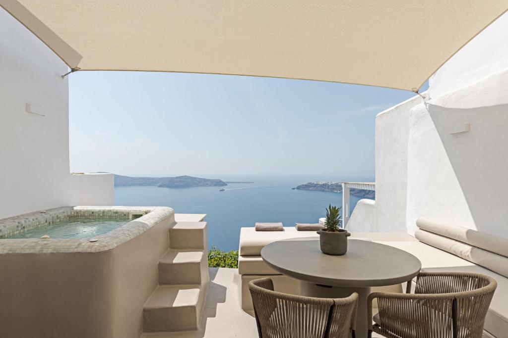 a patio with a table and chairs and a swimming pool at Seascape Villa by Caldera Houses in Imerovigli