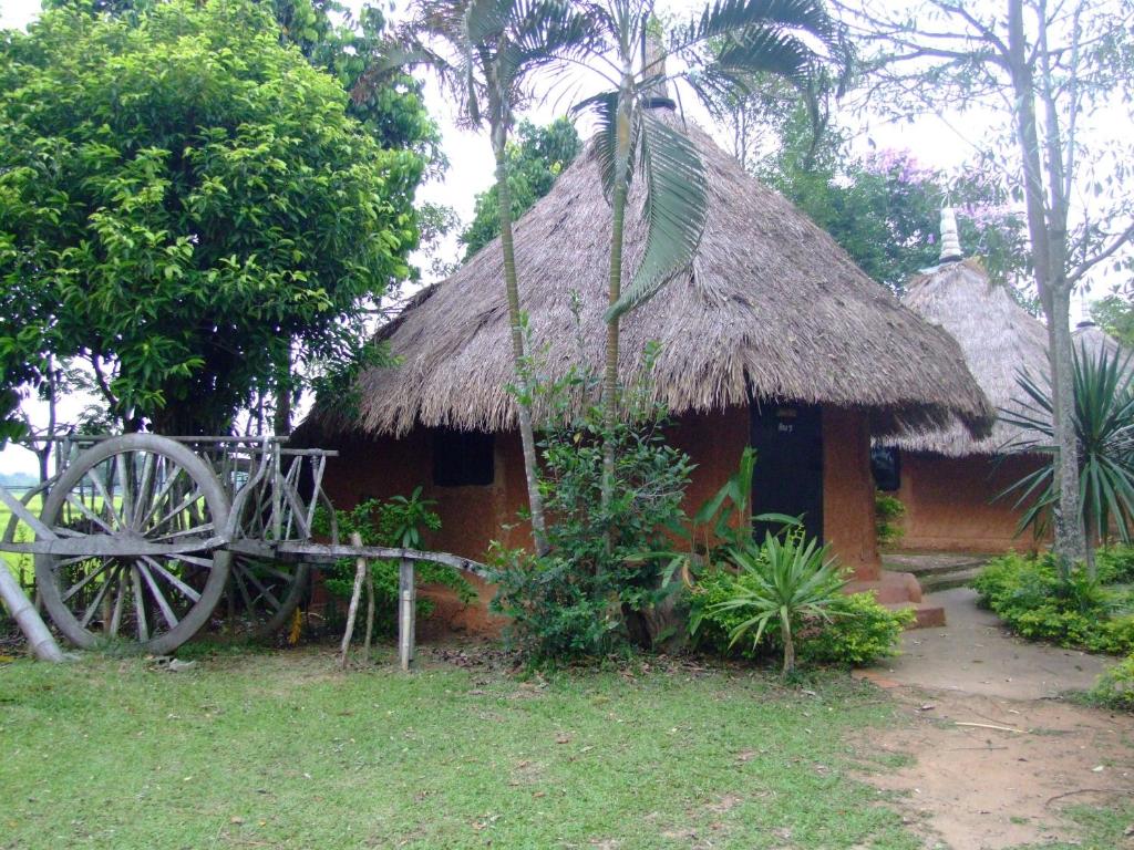 a small hut with a thatch roof and a wheel at Ban Din Resort Chiang Rai in Mae Chan