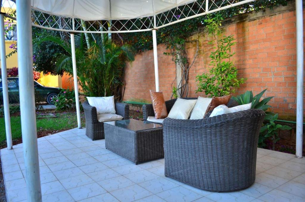 dwa wiklinowe krzesła i stół pod parasolem w obiekcie Room in Villa - The blue room is an accent of modernity in the silence of the surrounding garden w Antananarywie