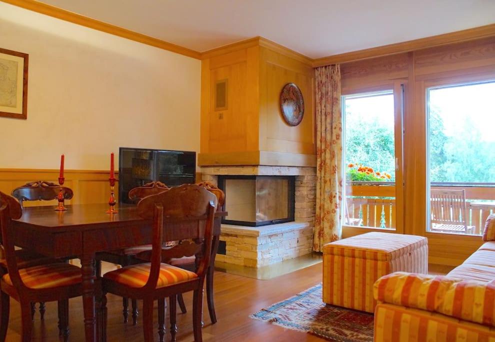 ein Wohnzimmer mit einem Tisch und einem Kamin in der Unterkunft Charming 3 bedroom on Jack Nicklaus golf course - Estoril in Crans-Montana