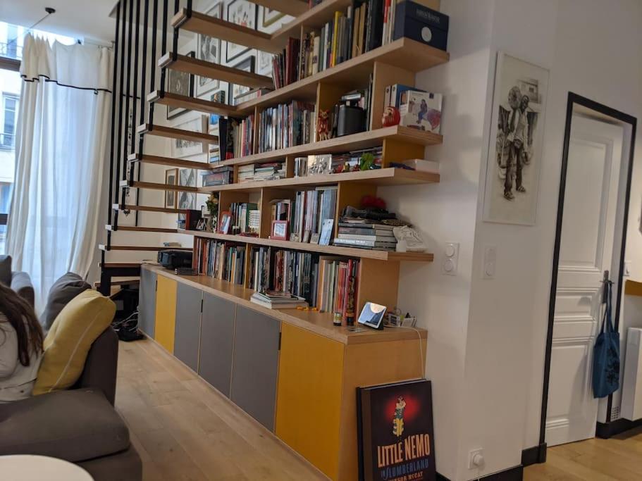 a living room with a book shelf filled with books at Maison loft rue de Belleville in Paris