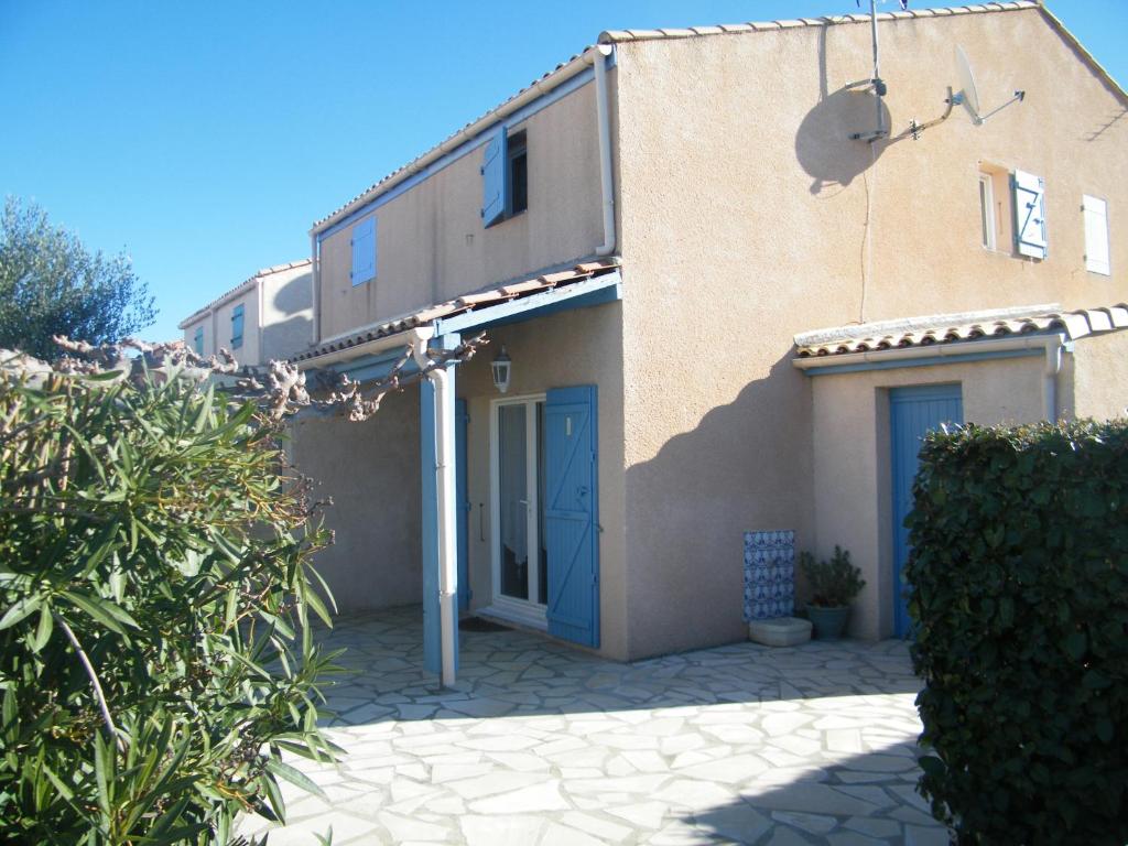 une maison avec une porte bleue sur son côté dans l'établissement Coquet Pavillon classé meublé de tourisme Narbonne Plage, à Narbonne-Plage