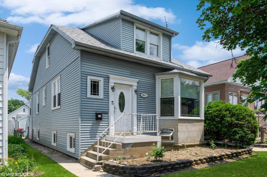 een blauw huis met een veranda en een trap bij A terrific house for a large group. in Chicago